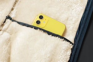 Detailed view of the thick beige faux lamb wool lining and deep inner pocket with a phone