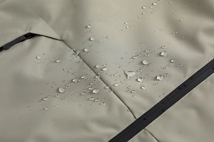 Dettaglio del tessuto impermeabile con gocce d'acqua su una giacca outdoor grigio-verde