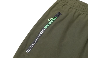 Dettaglio dei pantaloni sportivi verde militare con tasche con zip e vita elastica