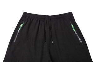 Dettaglio vita elastica e tasca con zip e nastro sport verde neon sui pantaloni sport