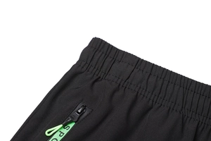 Dettaglio vita elastica e tasca con zip con etichetta verde SPORT su pantaloni sportivi