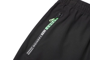 Dettaglio vita elastica e tasca con zip su pantaloni sportivi neri da esterno