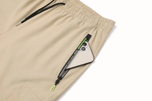 Dettaglio di pantaloni sportivi kaki con tasca a zip e fettuccia con logo sportivo