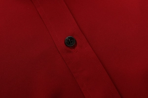 Dettaglio macro del tessuto camicia bordeaux con trama fitta e chiusura a bottone nero