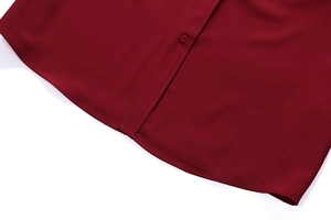 Close-up of the curved hem and button placket on a deep red long sleeve shirt