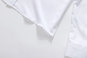 Close-up of clean stitching and hem detail on a white long-sleeved business shirt