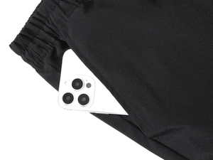Detail view of men's athletic pants showing elastic waistband and large side pocket with phone