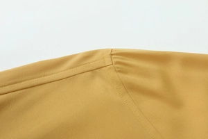 Dettaglio delle cuciture della spalla della camicia giallo senape e texture del tessuto