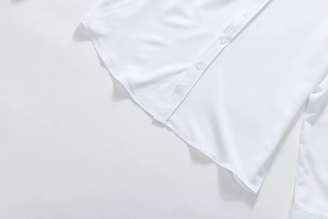 Detailed macro view of white business shirt hem with clean stitching and button placket