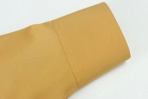 Dettaglio del tessuto elasticizzato giallo zenzero con cuciture parallele a doppio ago