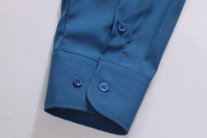 Detail view of deep teal shirt cuffs with precise stitching and matching blue buttons