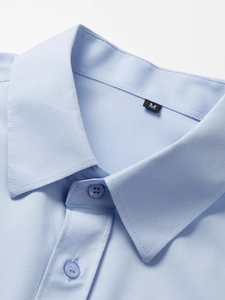 Detailaufnahme von hellblauem Hemdkragen mit hochwertigen Knöpfen und feinen Nähten