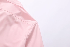 Close-up of the light pink shirt collar and shoulder stitching with fine matte texture