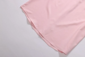Close-up of pink shirt hem showing premium double-stitched seams and smooth fabric