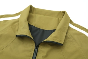 Détail du col de la veste vert olive avec bandes blanches et fermeture éclair noire robuste