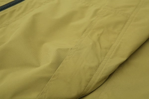 Détail de la veste coupe-vent jaune moutarde avec double couture et fermeture éclair noire