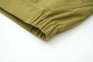 Détail macro de poignets élastiques et tissu sergé vert olive sur une veste de loisirs