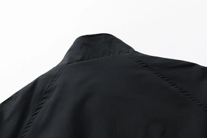 Détail du col montant et des coutures de manches raglan sur la veste noire coupe-vent