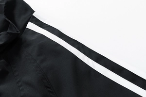 Détail de l'épaule de la veste avec des rayures blanches sur tissu polyester noir
