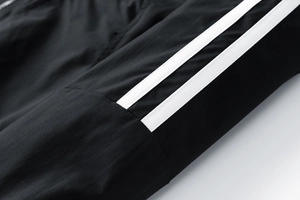Détail de la veste noire coupe-vent avec bandes blanches et texture tissée fine