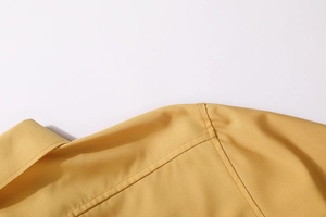 Detailed close-up of double-stitched collar and shoulder on mustard yellow work shirt