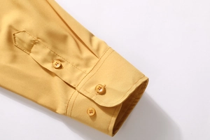 Detail of ginger yellow shirt cuff featuring three amber resin buttons and fine stitching