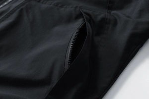 Gros plan sur la poche zippée d'une veste légère noire à rayures sportives