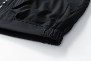 Détail de la veste noire montrant l'ourlet élastique et la texture du tissu coupe-vent