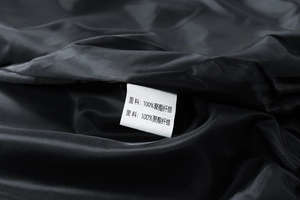 Détail de l'étiquette d'entretien montrant le tissu 100% polyester de la veste noire