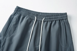 Détail du pantalon cargo avec taille élastique, cordon blanc et coutures contrastées