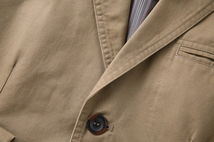 Detailed close-up of khaki cotton blazer with notch lapel and tortoiseshell button