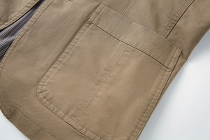 Detail of khaki cotton blazer featuring a large patch pocket and striped lining texture