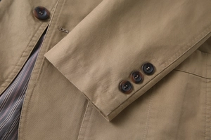Detailed macro view of khaki cotton twill fabric with marble texture buttons and striped lining