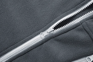 Close-up of grey polar fleece fabric texture with durable white plastic zipper detail
