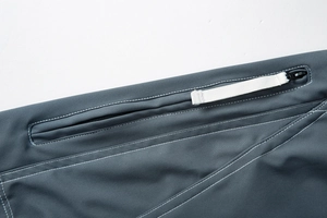 Détail du pantalon cargo gris foncé avec coutures blanches et poche à fermeture éclair YKK