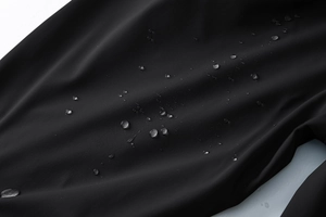 Macro di tessuto nero impermeabile che mostra l'effetto idrorepellente con gocce d'acqua