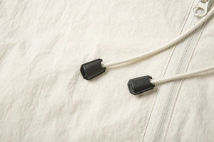 Detailed close-up of cream sun protection jacket with zipper and adjustable drawstring