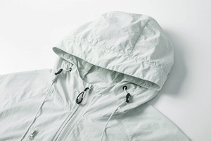 Detail of light gray sun protection hoodie with adjustable drawcord and zipper texture