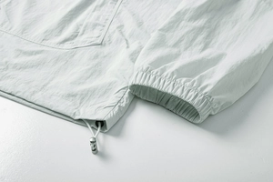Detail view of adjustable drawstring hem and elastic cuffs on breathable white sun jacket