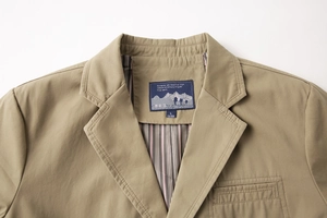 Dettaglio del blazer kaki con rever, fodera a righe ed etichetta del marchio sul collo