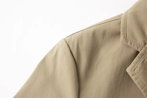 Dettaglio della cucitura della spalla e del risvolto di un blazer in cotone kaki chiaro