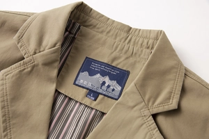 Dettaglio del colletto di un blazer kaki casual con fodera a righe ed etichetta