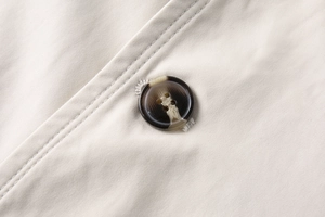 Dettaglio del bottone tartarugato e del tessuto in twill di cotone su un blazer beige
