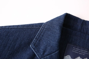 Détail du col en jean bleu foncé montrant les coutures soignées et la texture du sergé