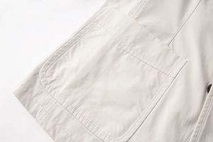 Dettaglio macro della tasca applicata con doppia cucitura su blazer in cotone beige