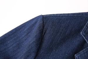 Gros plan détaillé des coutures d'épaule et de la texture sergé du blazer en jean