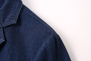 Détail du revers d'un blazer en denim bleu foncé montrant la texture du tissu sergé