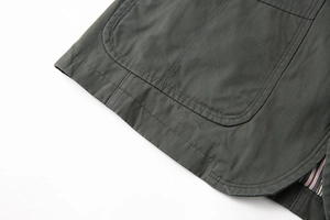 Dettaglio del blazer in cotone grigio con tasca rotonda e fodera a righe colorate