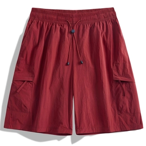 Detailed view of drawstring elastic waistband and flap cargo pocket on dark red shorts