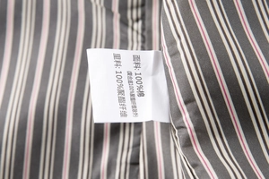 Dettaglio dell'interno del blazer con etichetta 100% cotone e fodera a righe sottili